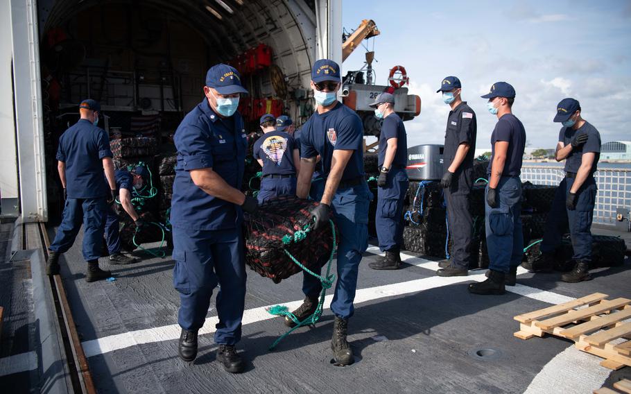 Crew members offload bales of seized drugs