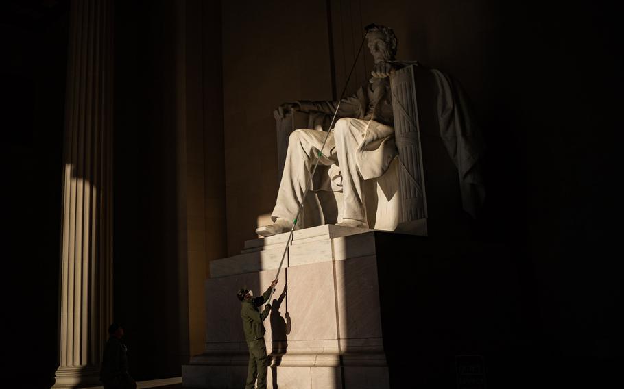 A National Park Service employee dusts the statue of President Abraham Lincoln at the Lincoln Memorial on Wednesday, May 18, 2022. 