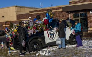 Three individuals holding flowers approach one of three memorials outside the Burnsville Police Department and City Hall building in Burnsville, Minn., on Tuesday, Feb. 20, 2024. Two police officers and a firefighter who responded to a domestic situation at a suburban Minneapolis home were killed early Sunday.