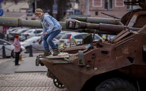 A child climbs on a rusty armored personnel carrier, part of a display of destroyed Russian military equipment in Kyiv, Ukraine, Thursday, March 28, 2024. (AP Photo/Vadim Ghirda)