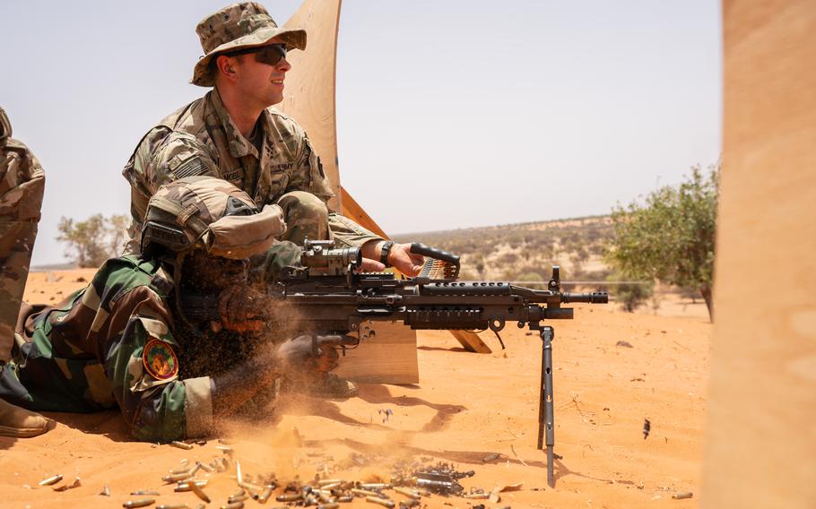 A Senegalese soldier fires an M249 squad automatic weapon while Maryland National Guardsman Sgt. Mathew Angell serves as a range safety officer during African Lion in Dodji, Senegal.