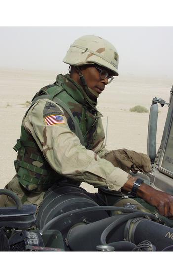 A soldier checks his vehicle’s oil.