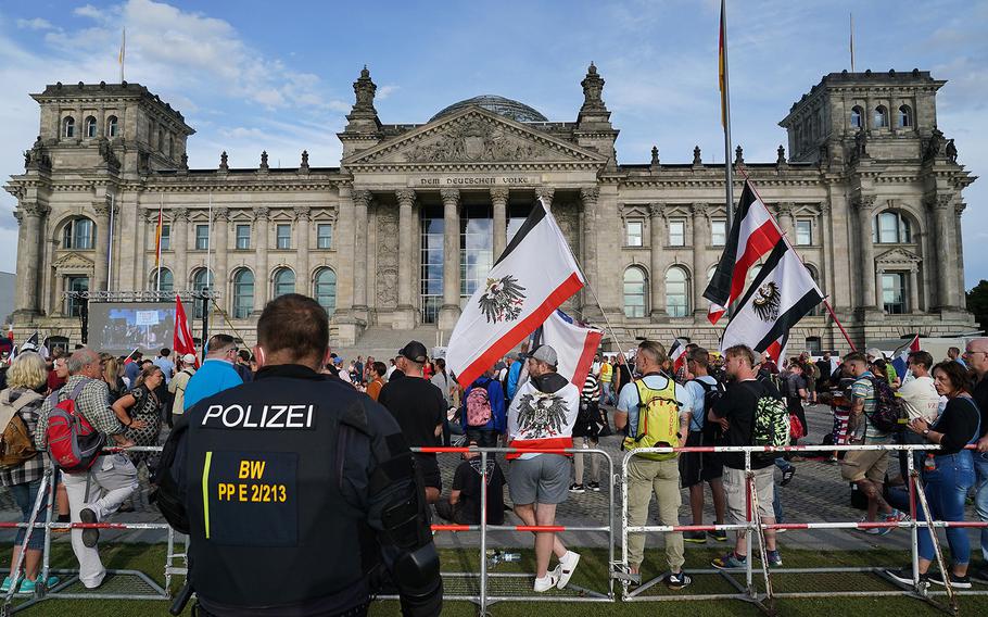 Riot police observe far-right protesters gathered outside the Reichstag during protests against coronavirus-related restrictions and government policy on Saturday, Aug. 29, 2020, in Berlin. 