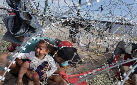 A group of Venezuelan migrants negotiate razor wire last month as they cross into the United States from Ciudad Juárez, Mexico. (MUST CREDIT: Washington Post photo by Michael Robinson Chávez)