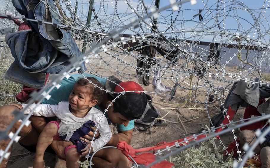 A group of Venezuelan migrants negotiate razor wire in September 2023 as they cross into the United States from Ciudad Juárez, Mexico. 