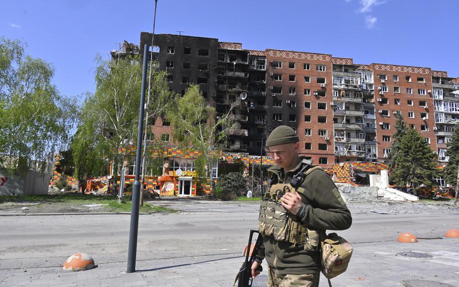 A Ukrainian soldier walks past damaged buildings.