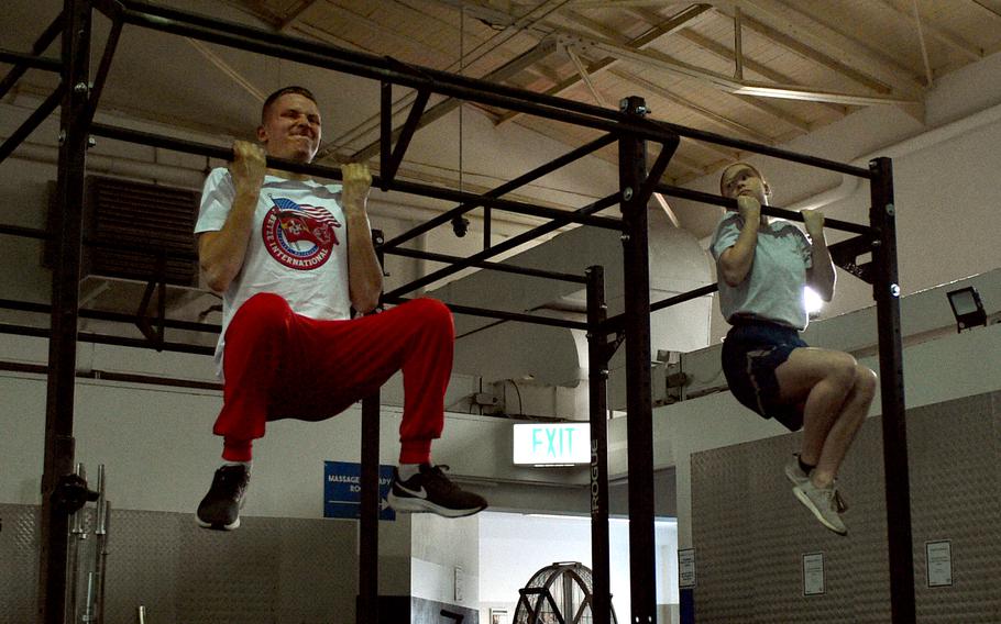Airman Emma Gantner, right, looks over at 1. FC Kaiserslautern midfielder Aaron Basenach toward the end of a flexed-arm hang challenge at Northside Gym on Ramstein Air Base, Germany, March 23, 2023, during a visit by the professional soccer team to the base. Gantner earned a German armed forces badge for military proficiency last year.