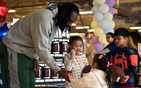 Khailey Olympia, center right, holds New England Patriot outside linebacker Matthew Judon's hand duirng an autograph event on March 23, 2024, at the Kaiserslautern Military Community Center on Ramstein Air Base, Germany. Kalani, center, and Khaiden, right, Khailey's older silbings, listen along.