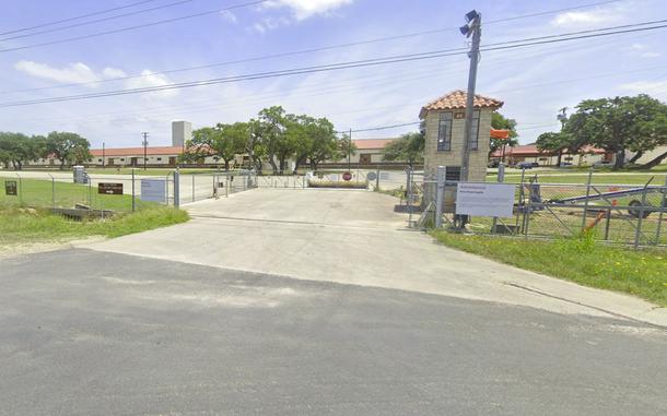 The gate of a military base, with red roofed buildings seen in the background.