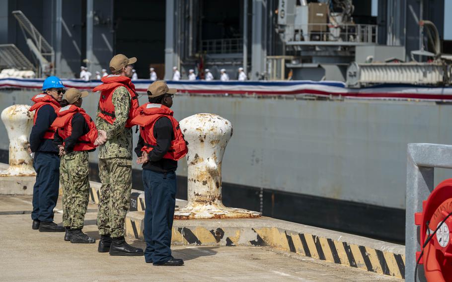 Line handlers stand by on the pier