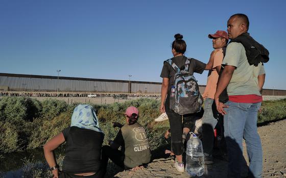 Migrants from Venezuela pause on Sept. 19, 2023, in Ciudad Juárez, Mexico, as they view the border wall separating the United States from Mexico. 