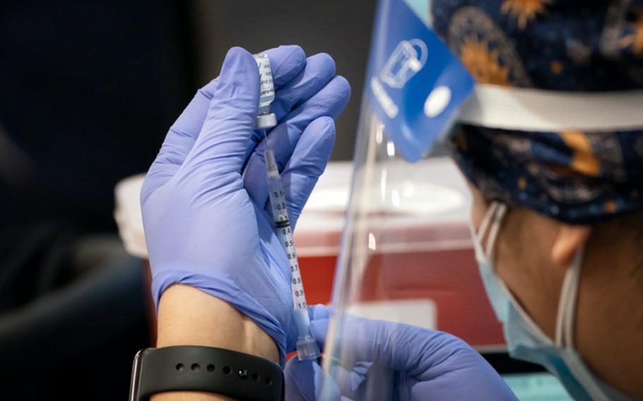 Registered nurse Darcey McCampbell measures a dose of the Pfizer COVID-19 vaccine in preparation for administering a shot in Brooklyn Center, Minnesota. 