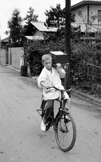 A child rides a bike with trays of food
