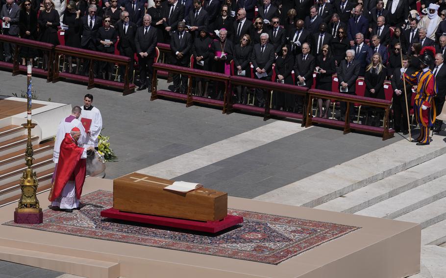 A plain wooden coffin with a cross on it sits on an altar.