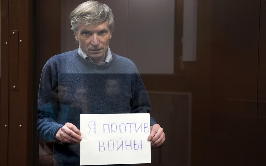 Alexei Gorinov holds a sign "I am against the war" standing in a cage during hearing in the courtroom in Moscow, Russia, Tuesday, June 21, 2022. Moscow's Meshchansky District Court ruled Tuesday that Alexei Gorinov, a member of the municipal council in one of Moscow's districts, should stay in custody pending his trial on charges of discrediting the country's armed forces.