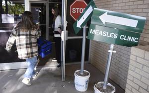 Health department staff members enter the Andrews County Health Department measles clinic carrying doses of the measles, mumps and rubella vaccine, Tuesday, April 8, 2025, in Andrews, Texas. (AP Photo/Annie Rice)