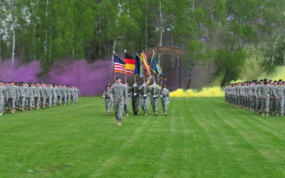 The 7th Army Noncommissioned Officer Academy's Warrior Leader Course participants march out of the wood lines through purple and yellow smoke at Camp Normandy field in in Grafenwoehr, Germany, on May 7, 2015. 