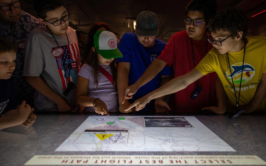 Several people, including children, hover over an interactive display in a dim room.