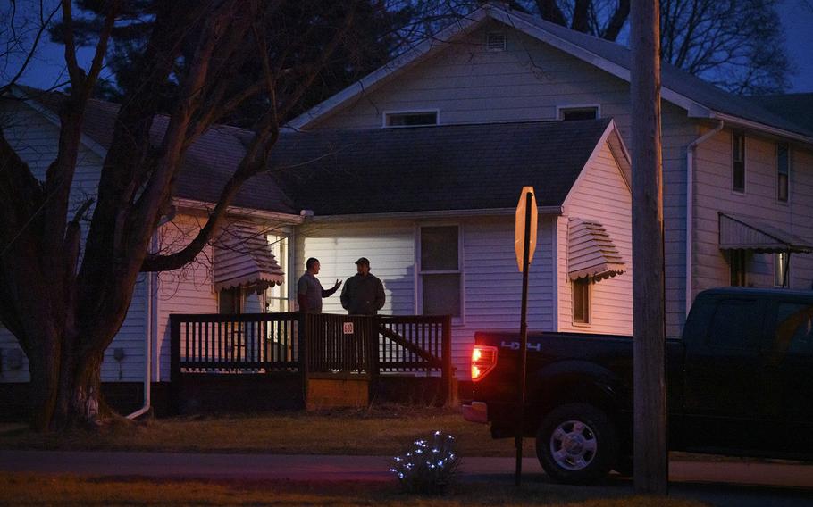 Scott Berresford talks with a neighbor on his porch in East Palestine, Ohio. Berresford lives one block from the site of the Norfolk Southern train derailment. 