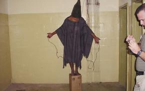 FILE - This late 2003 photo obtained by The Associated Press shows an unidentified detainee standing on a box with a bag on his head and wires attached to him in the Abu Ghraib prison in Baghdad, Iraq. A trial scheduled to begin Monday, April 15, 2024, in U.S. District Court in Alexandria, Va., will be the first time that survivors of Iraq’s Abu Ghraib prison will bring their claims of torture to a U.S. jury. Twenty years earlier, photos of abused prisoners and smiling U.S. soldiers guarding them shocked the world. (AP Photo, File)