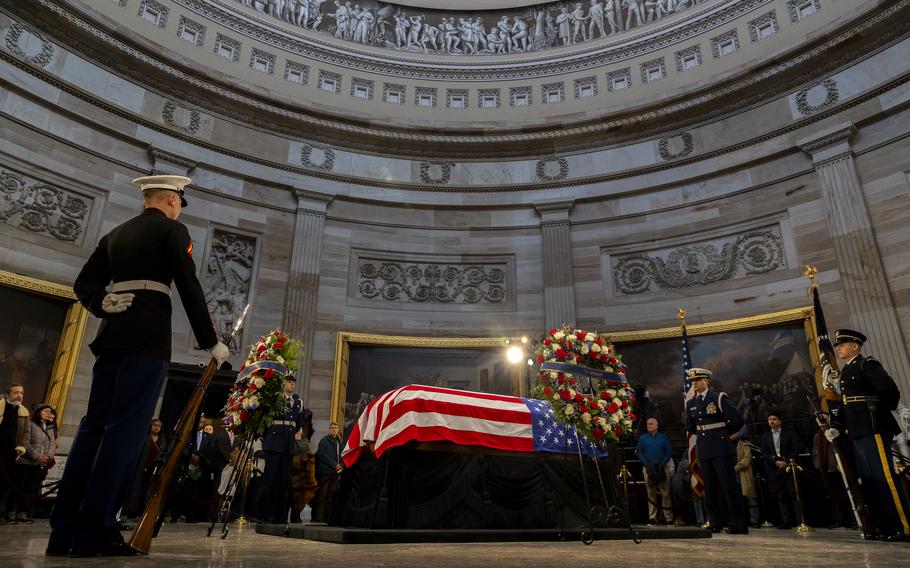 Carter’s flag-draped casket in the Capitol rotunda, with an honor guard standing by.