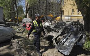 An emergency worker walks by heavily damaged cars.
