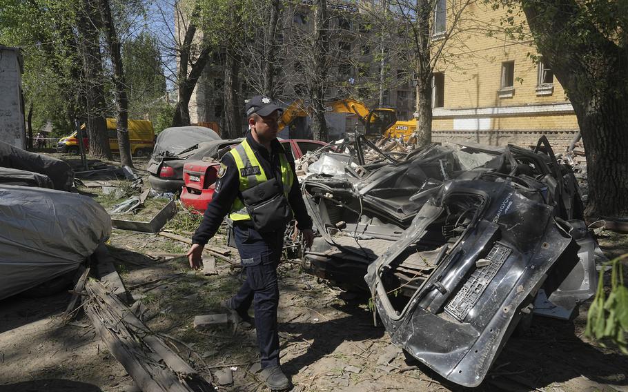 An emergency worker walks by heavily damaged cars.