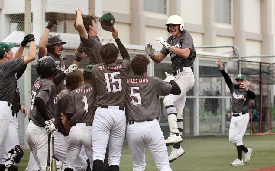 Kubasaki's Asher Romnek is mobbed by teammates following his home run; ccoach Aaron Fisk captures the moment on his phone.