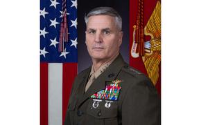 Christopher Mahoney posing for his official military photo with flags behind him.