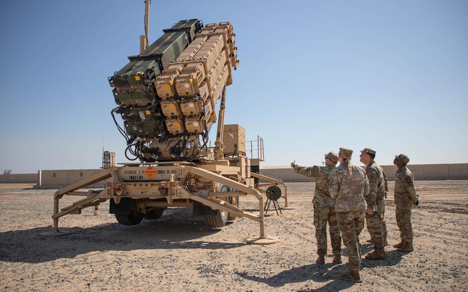 Col. Peter Gilbert points at a Patriot missile launcher while talking to a group of soldiers.