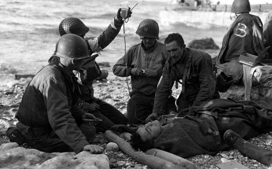 Nurses administer a plasma transfusion to a wounded survivor of a landing craft at ''Fox Green'' sector portion of Omaha Beach. The Soldiers are from the 16th Infantry Regiment, 1st Infantry Division. 
