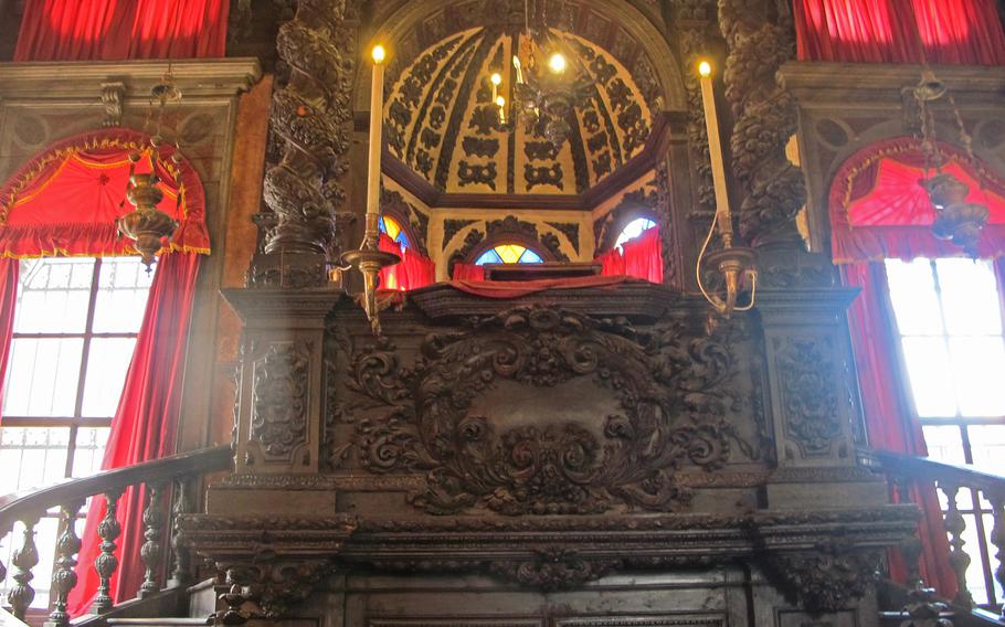 Inside the Levantine synagogue in Venice. It’s hushed and glowing from natural light and candelabra reflecting off the dark, intricate woodworking. The synagogue is one of five located in the city’s former Jewish ghetto. 