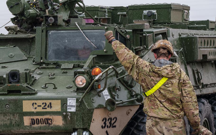 A soldier ground guides a Stryker.