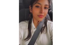A woman in a white collared shirt smiling slightly for a selfie.