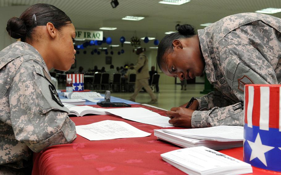 A service member watches another service member fill out paperwork