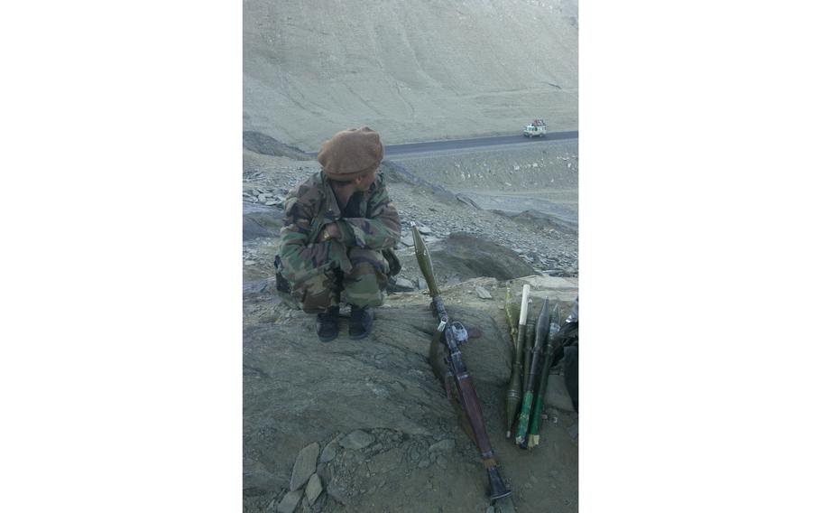 A Northern Alliance fighter perches atop a hill near Maidanshar [Maidan Shahr], Afghanistan, overlooking the road to Kabul on Nov. 23, 2001.