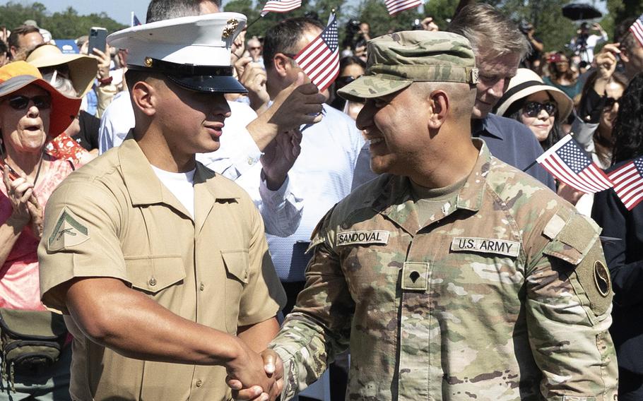 US service members from the Army and the Marine Corps shaking hands on becoming US Citizens.