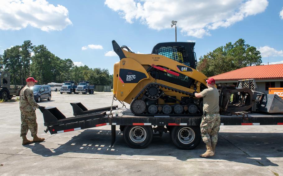 Air Force Tech Sgt. James Bishop and Staff Sgt. Dustin Hart, heavy equipment operators, load a skid-steer onto a trailer Monday, Sept. 26, 2022, ahead of Hurricane Ian response efforts at Camp Blanding Joint Training Center in Starke, Fla. Some National Guard troops will mobilize to hurricane-affected areas to remove road debris as part of disaster response efforts.