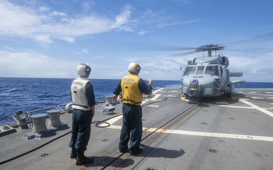 Sailors help direct an MH-60R Seahawk helicopter onto the guided-missile destroyer USS Sampson in the South Pacific, Jan. 19, 2022. 