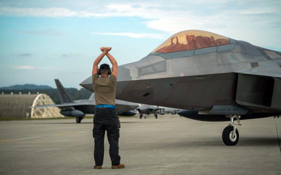 An airman marshals an F-22A Raptor assigned to the 3rd Wing into position at Kadena Air Base, Okinawa, Friday, Nov. 4, 2022.