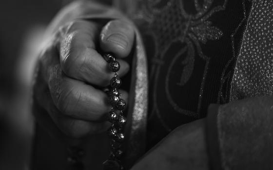 A man holds a Catholic rosary.
