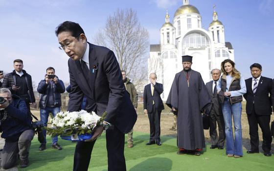Japanese Prime Minister Fumio Kishida, front, lays the flowers at a church in Bucha, a town outside Kyiv that became a symbol of Russian atrocities against civilians, in Ukraine, Tuesday, March 21, 2023.(Iori Sagisawa/Kyodo News via AP)