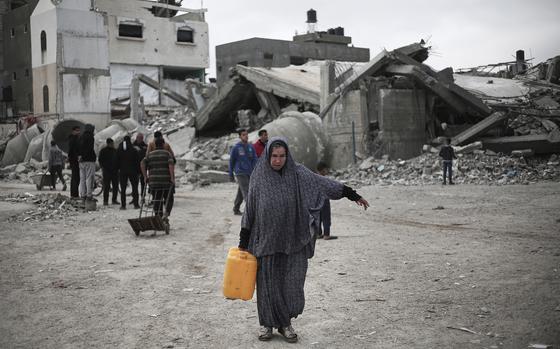 A Palestinian woman carries a water container to a refugee camp in Rafah in the southern Gaza Strip on Feb. 27, 2024.