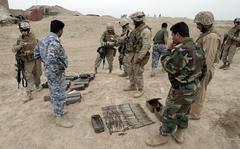 Members of 2nd Battalion, 3rd Marine Regiment look over part of a weapons cache discovered by the Marines and members of the Iraqi Civilian Watch outside of Subyhat, Iraq, March 13, 2008. 