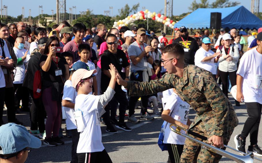 A member of the III Marine Expeditionary Force Band high-fives an athlete during the Kadena Special Olympics' opening ceremony at Kadena Air Base, Okinawa, Dec. 9, 2023.