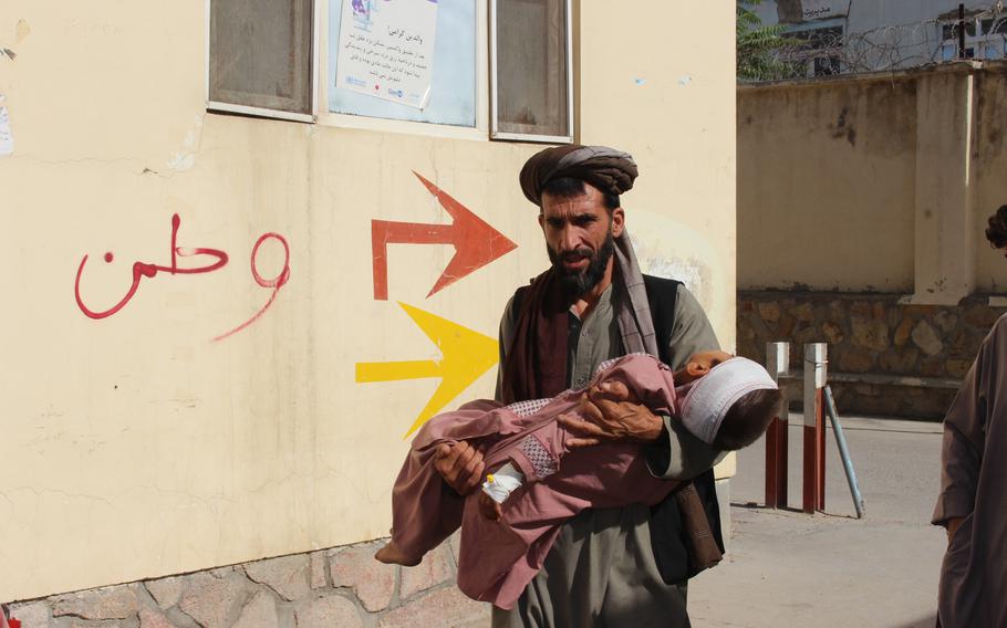 An Afghan civilian carry a wounded child to the hospital after he was injured during fighting between Taliban and government in Badghis province, northwest of Afghanistan, Wednesday, July 7, 2021.  