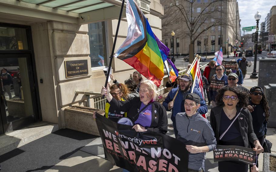 Protesters march holding signs and waving flags.