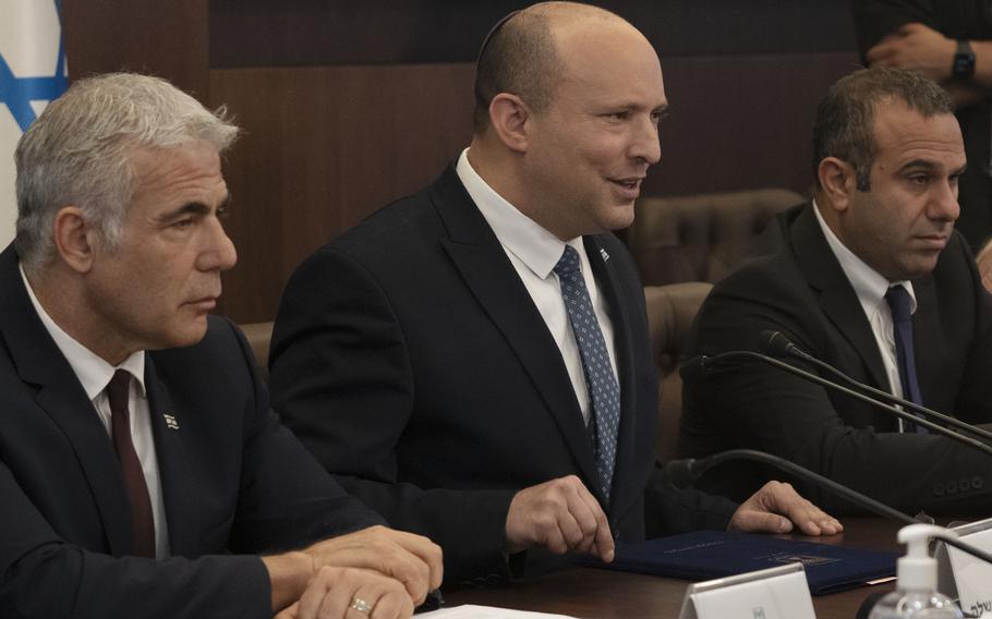 Israeli Prime Minister Naftali Bennett, center, makes a statement at the start of the weekly cabinet meeting seated next to Foreign Minister Yair Lapid, left, in Jerusalem, Sunday, May 8, 2022.
