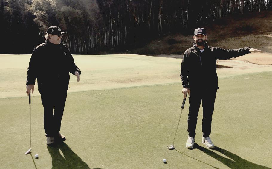 Two men stand on a golf course in Japan.
