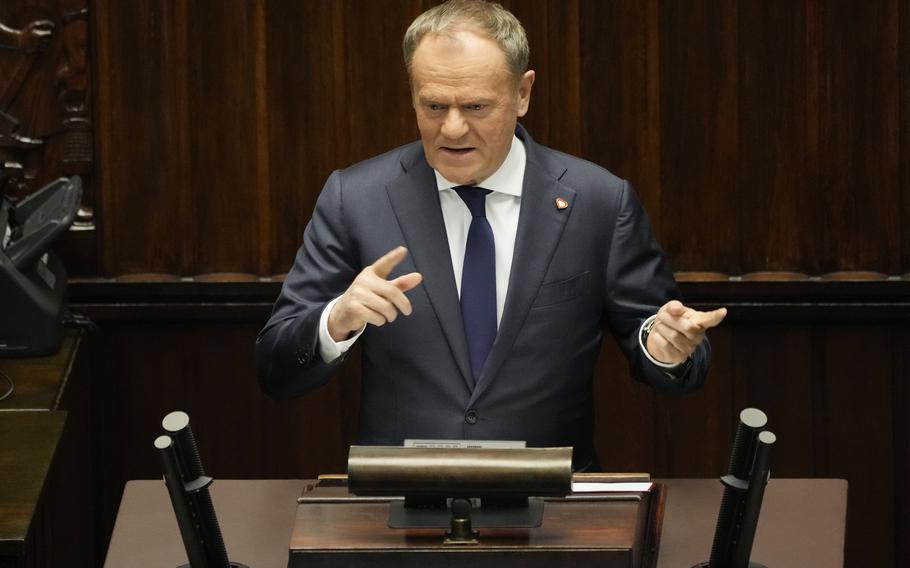 A man in a suit gestures with both hands at a podium.